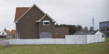 Een huis, grasveld en bedrijfsgebouw tonen de overgang van landelijkheid naar stedelijkheid